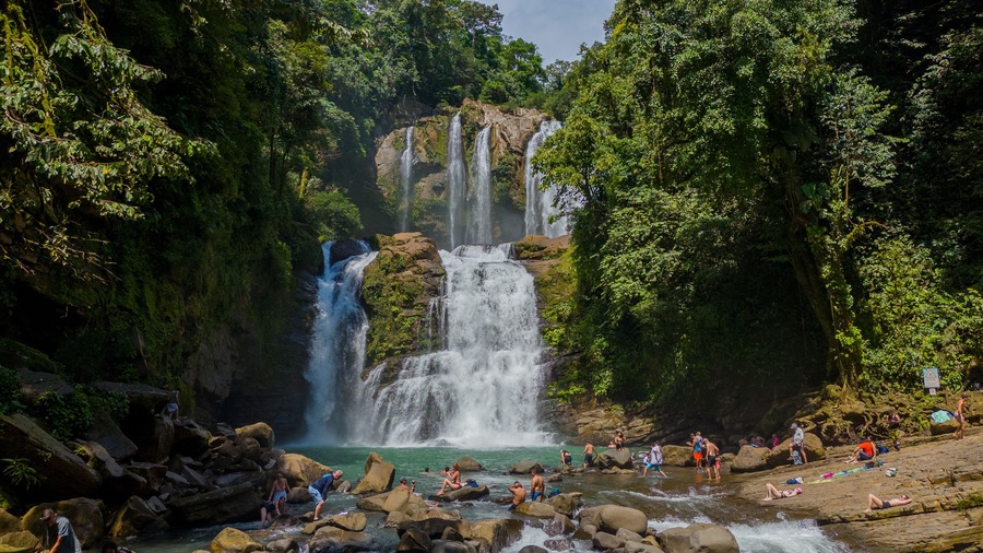 Nauyaca Waterfall in Perez Zeledon, San Jose, Costa Rica. Aerial drone footage of beautiful multi-stage waterfall. With Tourists swimming and enjoying the waterfall.