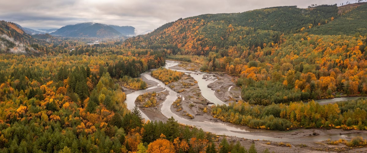A river winding through a forested valley with autumn foliage.