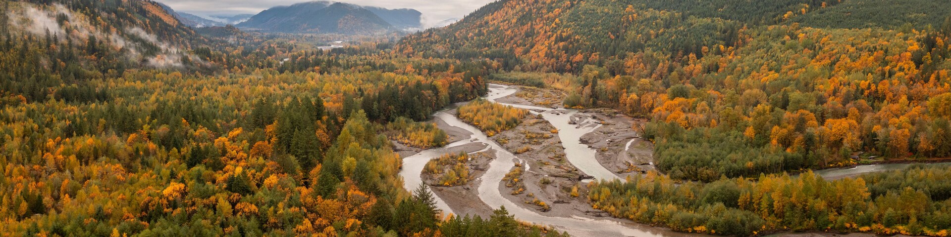 A river winding through a forested valley with autumn foliage.