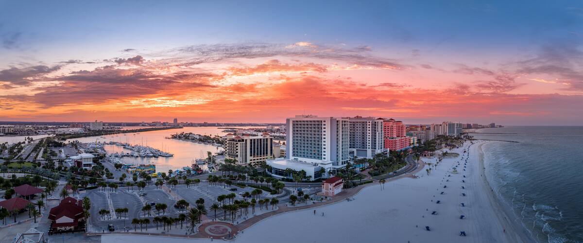 Row of hotels line Clearwater beach near Tampa with white sand colorful sunrise sky