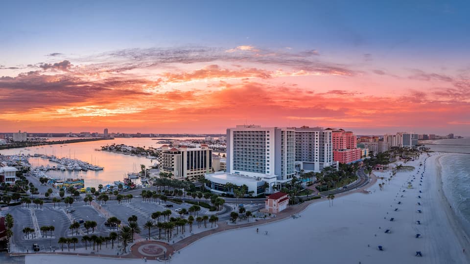 Row of hotels line Clearwater beach near Tampa with white sand colorful sunrise sky