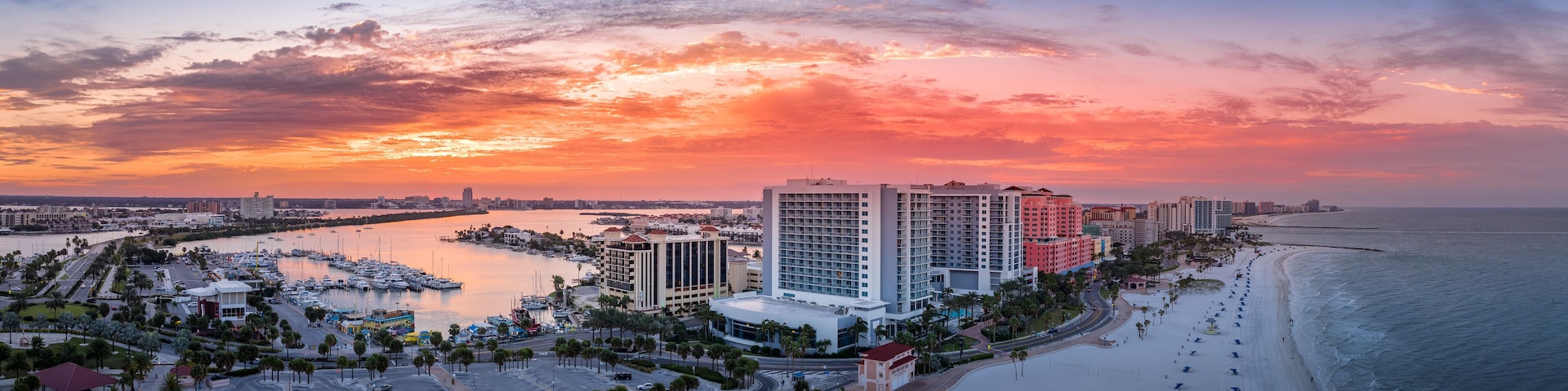 Row of hotels line Clearwater beach near Tampa with white sand colorful sunrise sky