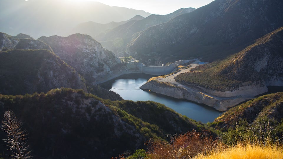 A mountainous landscape with a lake surrounded by hills and sparse vegetation.