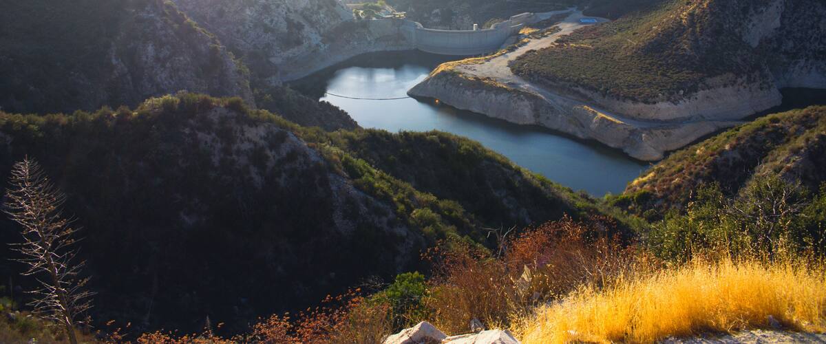 A mountainous landscape with a lake surrounded by hills and sparse vegetation.