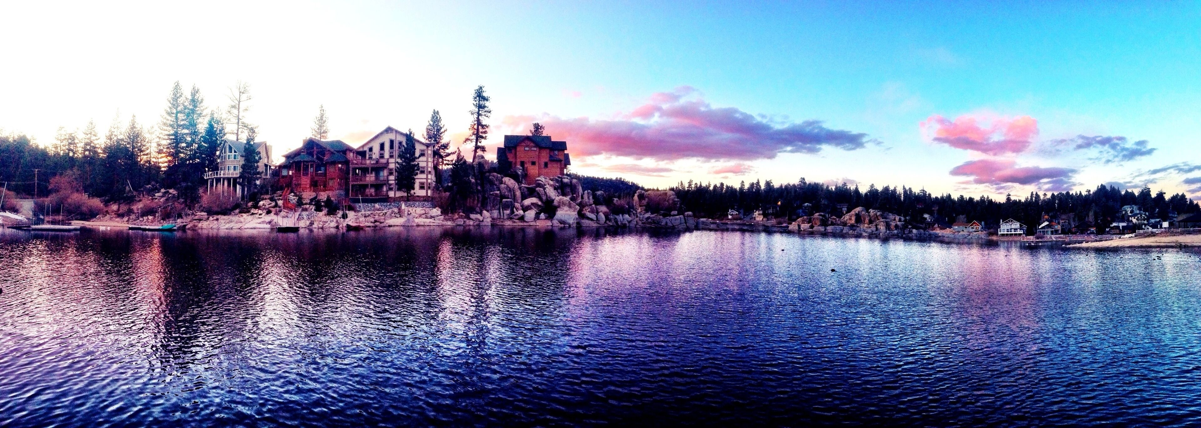 A lakeside village with wooden houses and a prominent stone building.