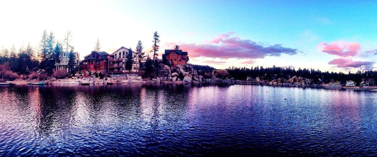 A lakeside village with wooden houses and a prominent stone building.
