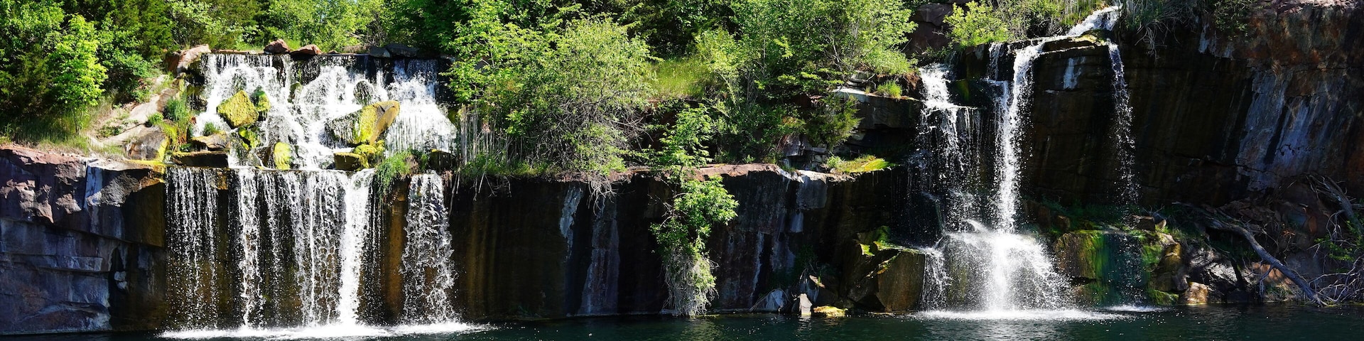 Una cascada se precipita en un lago cristalino rodeado de un bosque tupido.