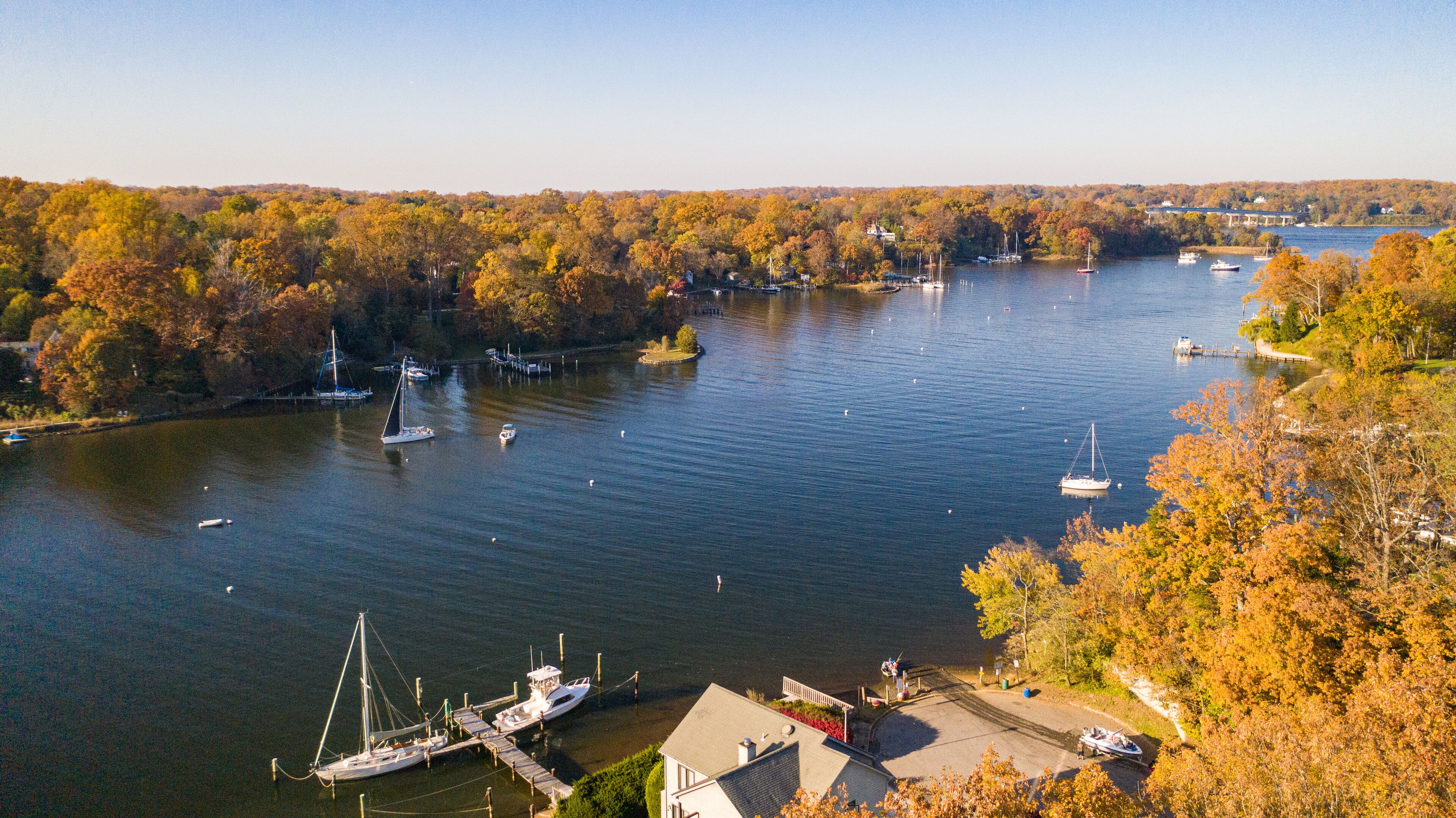 A river with boats, surrounded by autumn-colored trees.