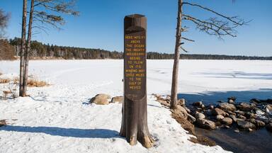 A wooden signpost in a snowy landscape with a clear blue sky.