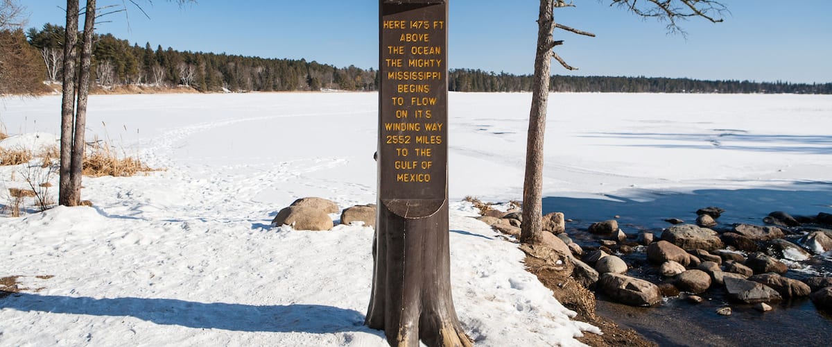 A wooden signpost in a snowy landscape with a clear blue sky.