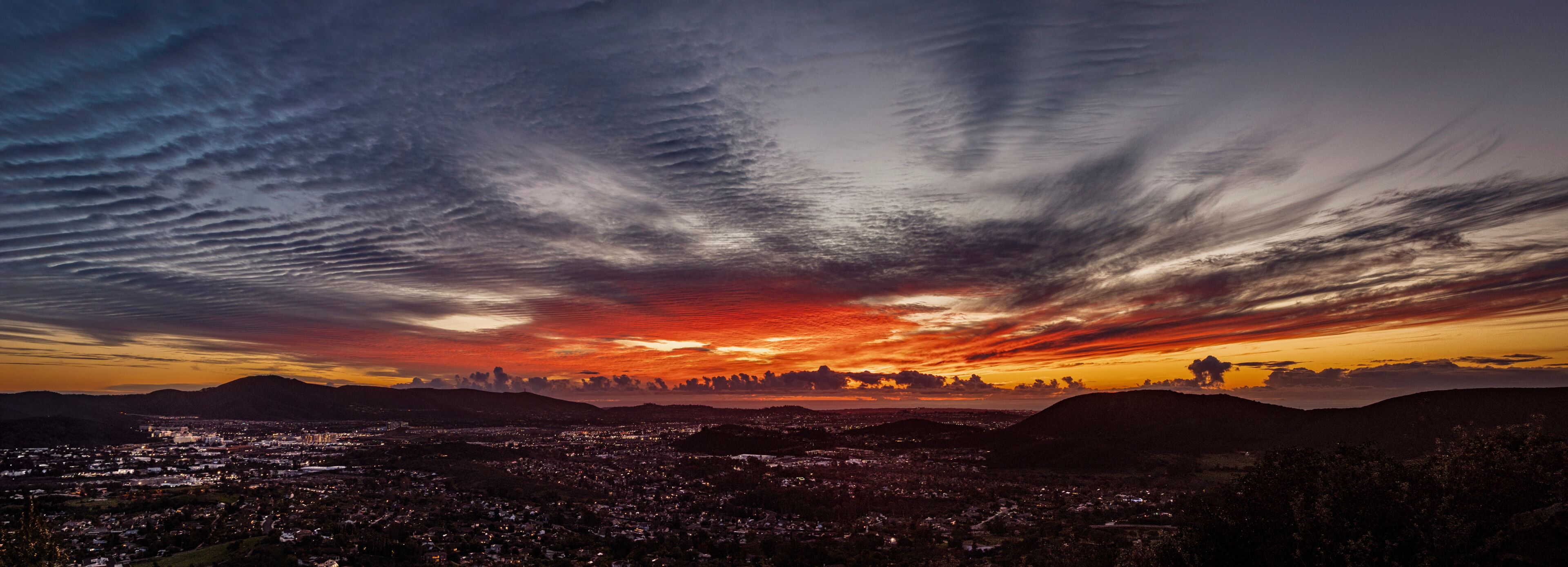 A beautiful sunset  from a hill overlooking a city with storm clouds.  The view is from Escondido Ca looking west toward San Marcos,Carlsbad and Oceanside Ca