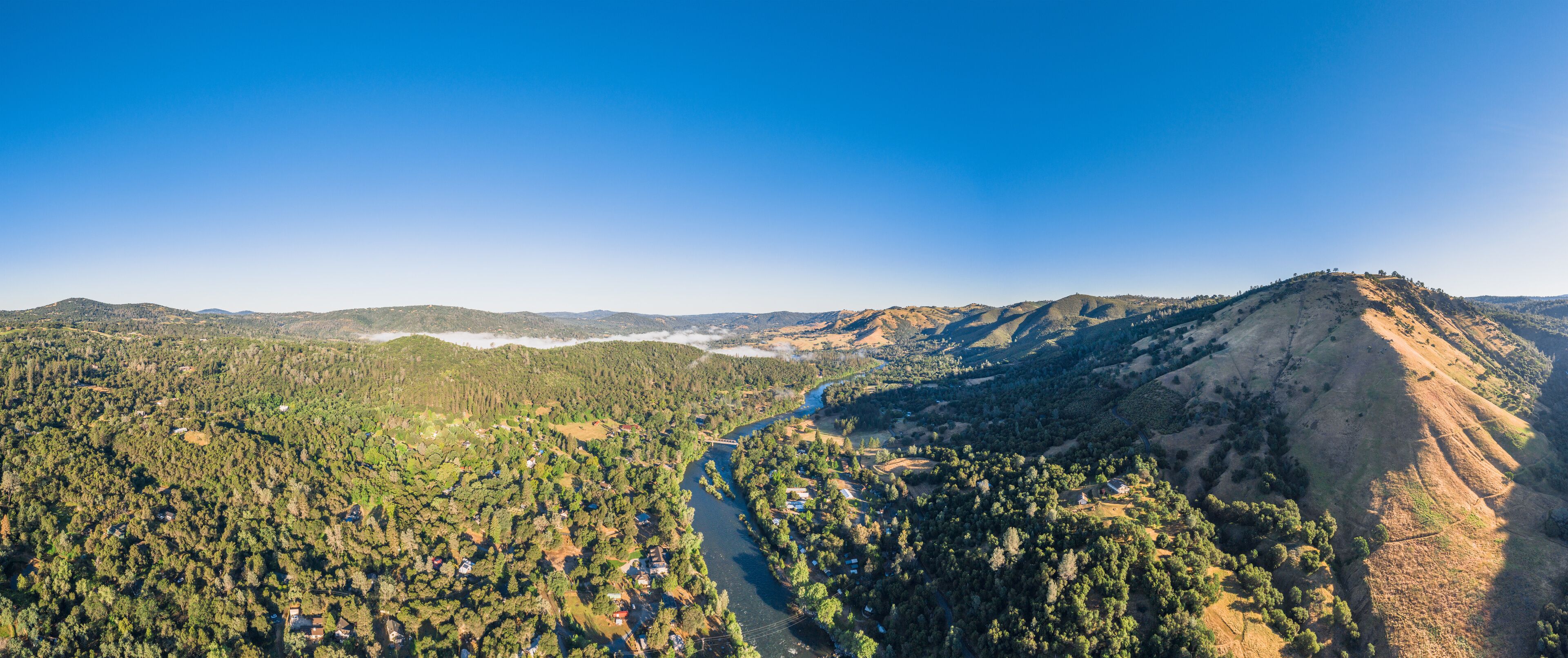 A mountainous landscape with a river winding through a forested valley.