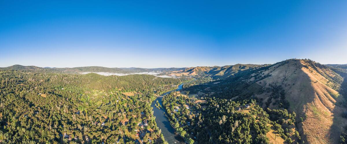 A mountainous landscape with a river winding through a forested valley.