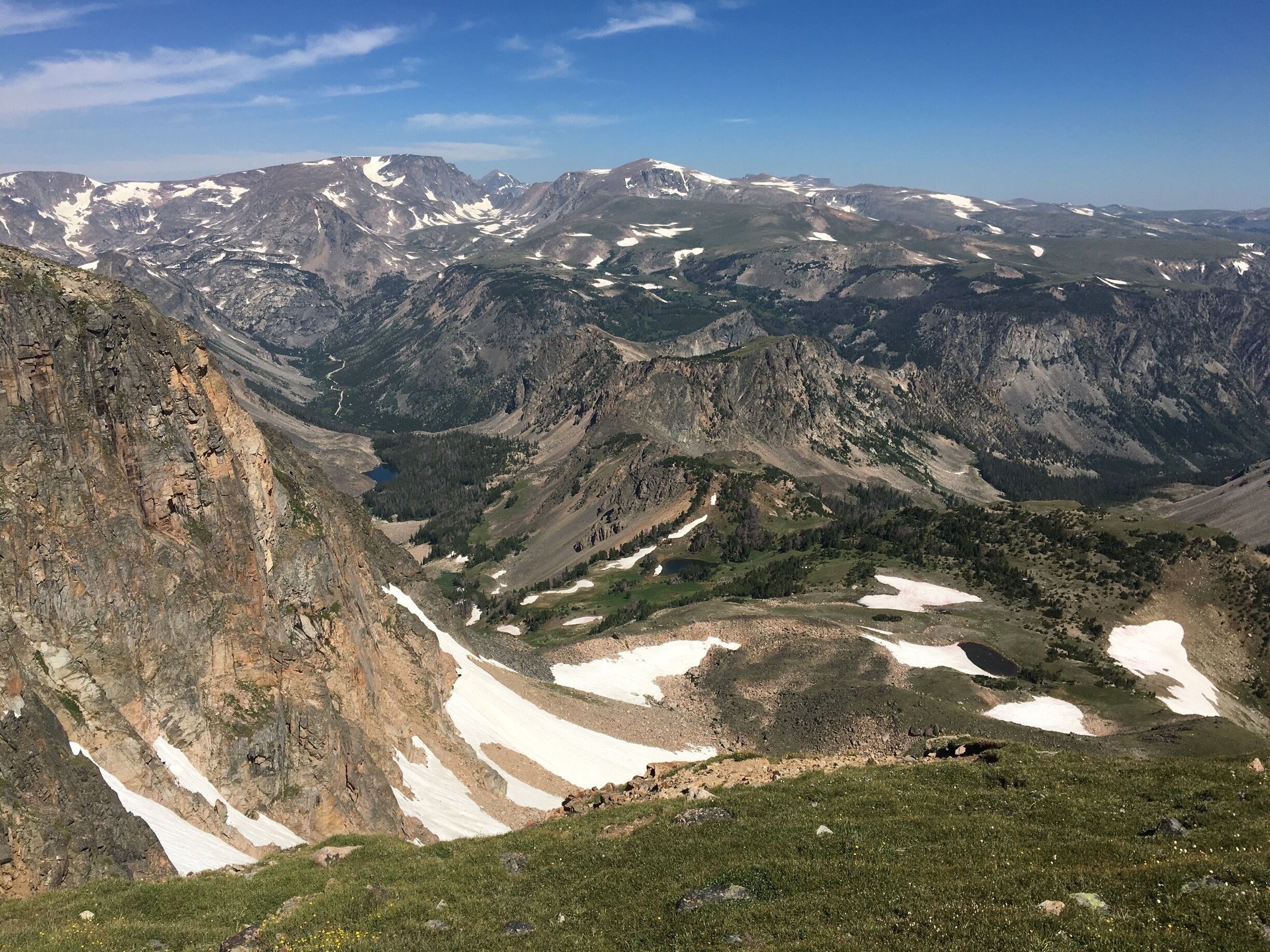 A mountainous landscape with snow patches and a clear sky.
