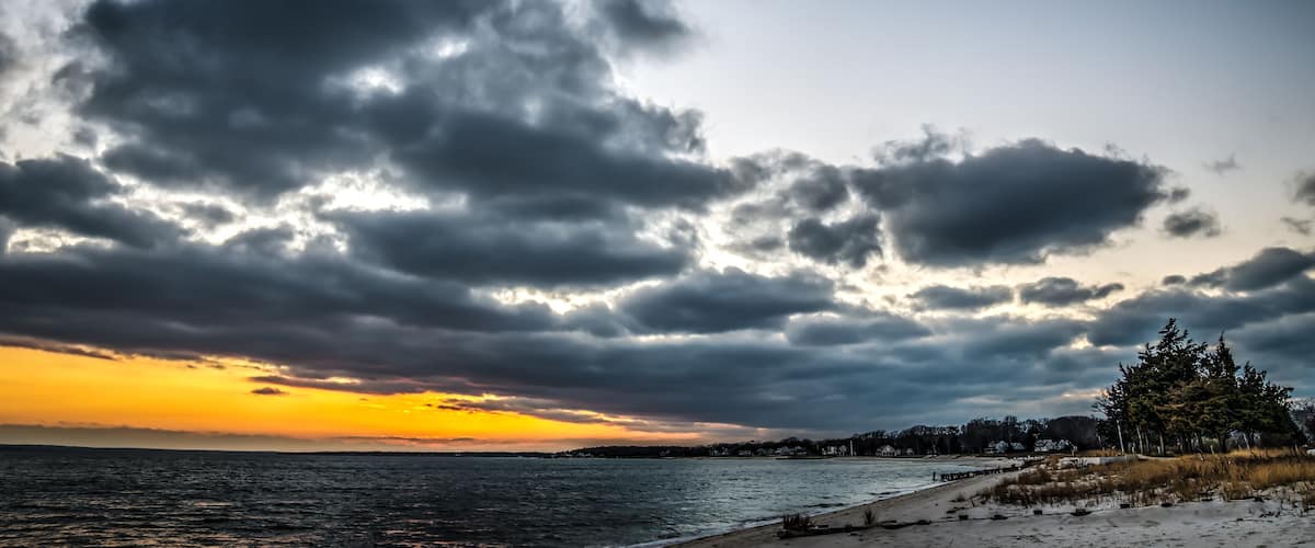 A beach with a cloudy sky and a sunset.