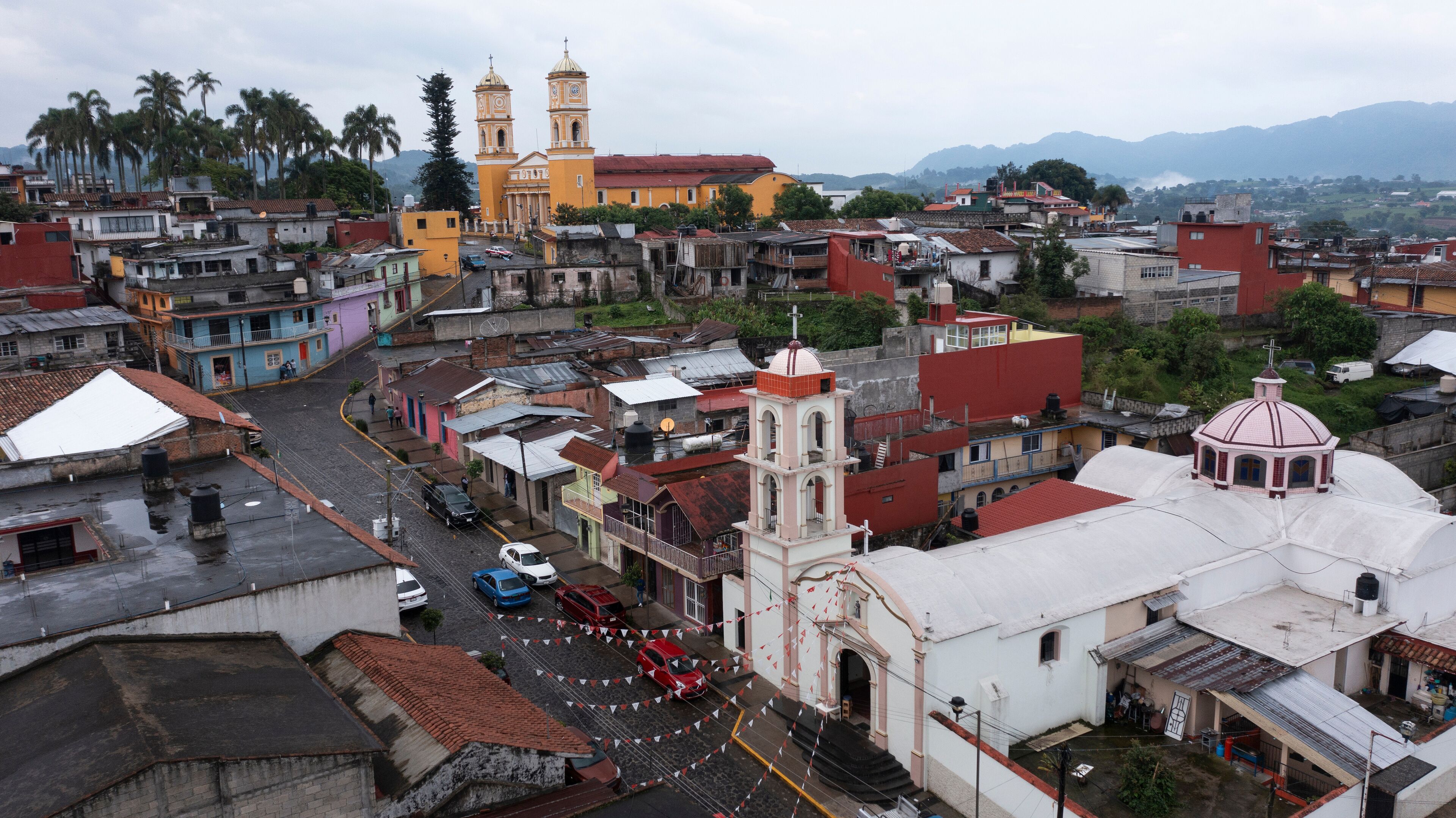 A cityscape with a prominent church with two towers, a mix of colorful buildings, and a mountainous backdrop.