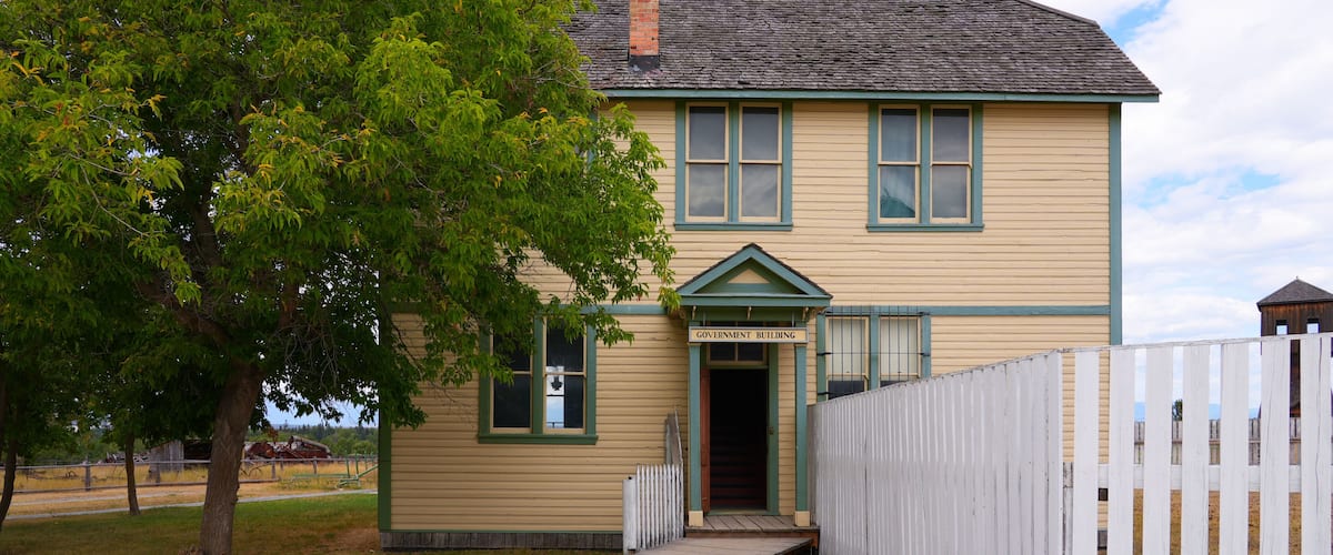 A yellow building with a green trim and a sign that reads "Government Building."