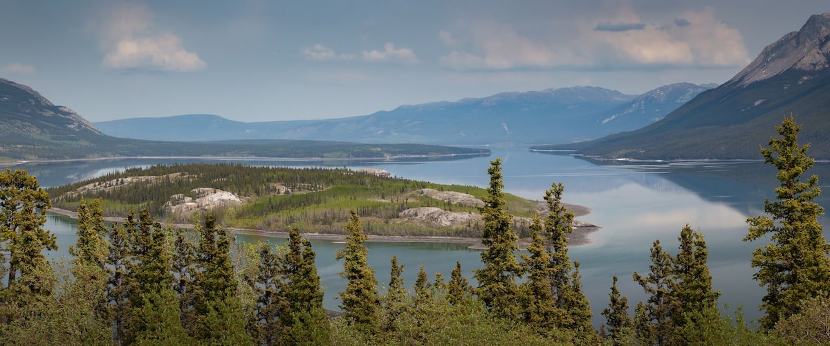A lake surrounded by mountains and dense forests.