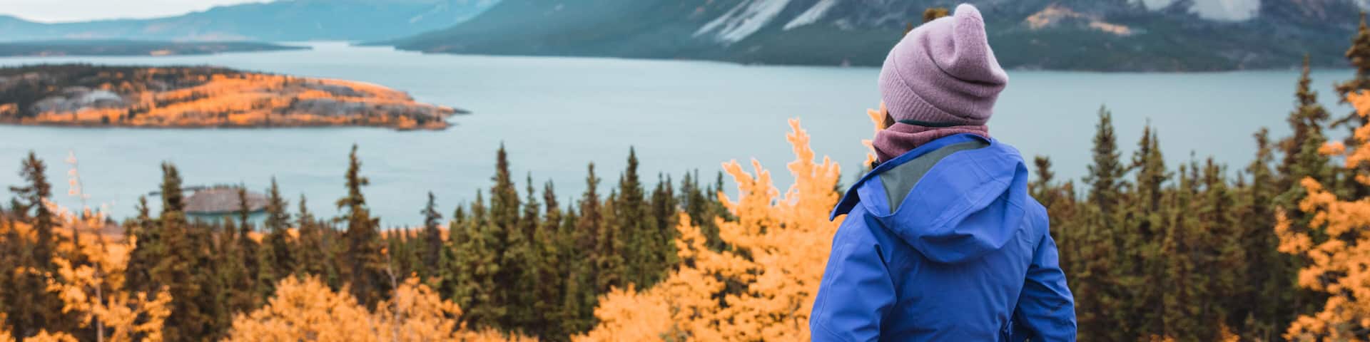 Hiker hiking at Bove island on Tagish Lake, Yukon during Skagway road trip Alaska cruise. Nature outdoors woman in mountains landscape background. USA travel autumn destination panoramic.