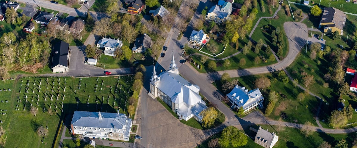 An aerial view of a residential area with houses, a church, and a cemetery.