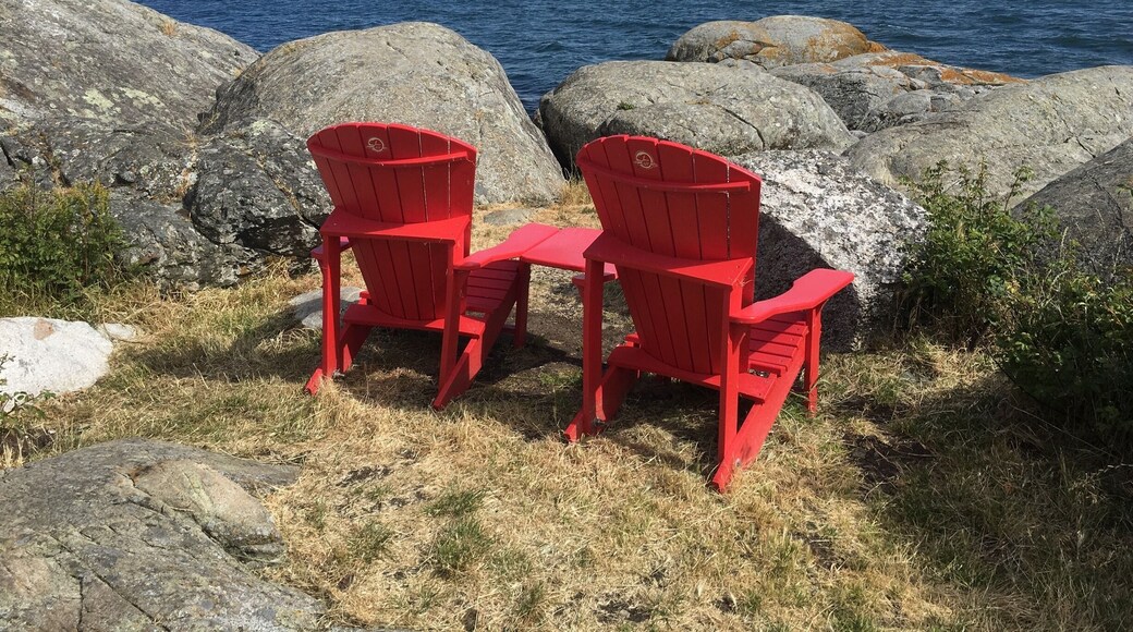 Two red chairs set out amongst some rocks at the site of Fisgard Lighthouse in Victoria, BC. #BeachBound #victoria