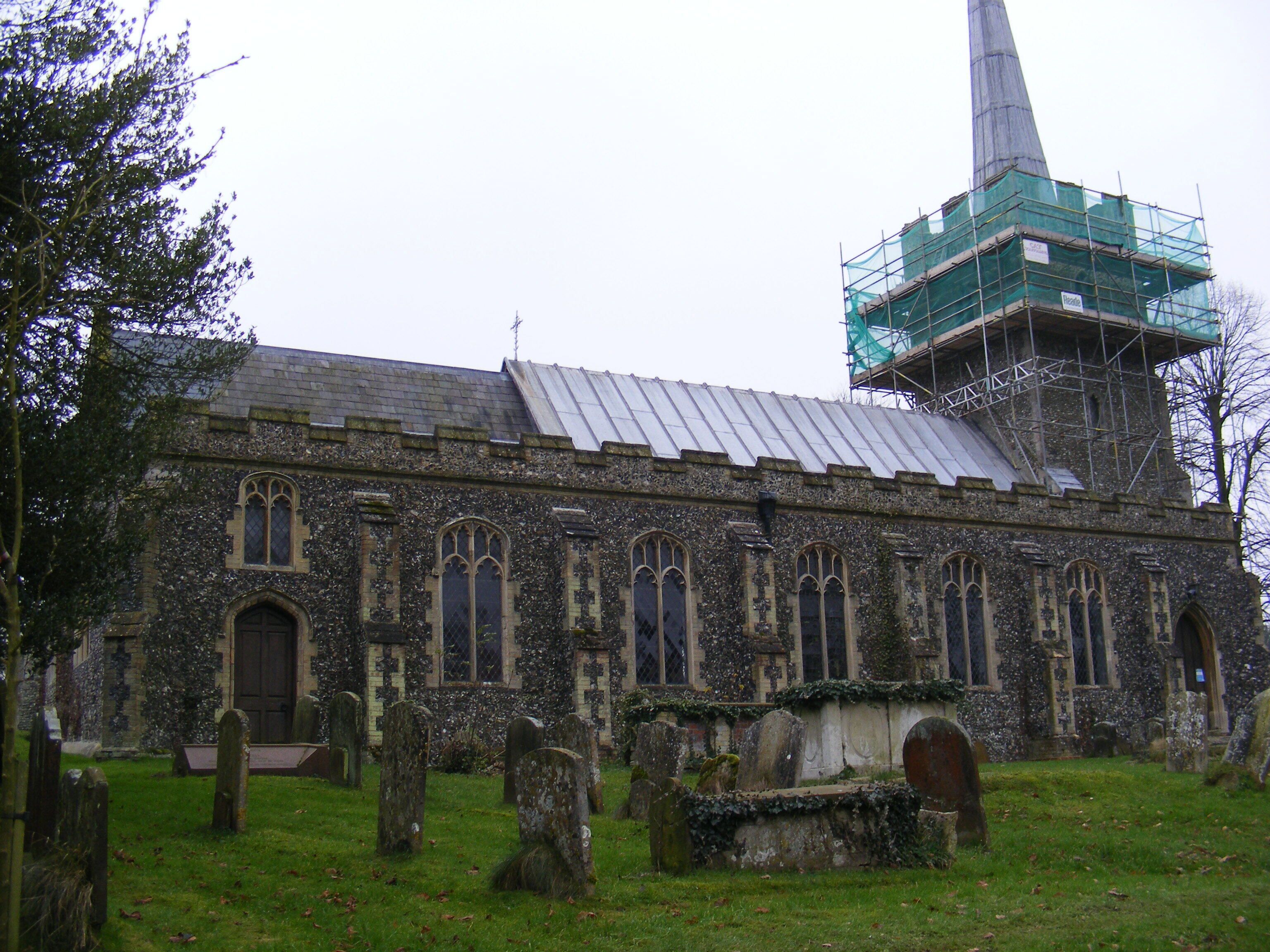 A historic church with a tall spire and a graveyard in front.