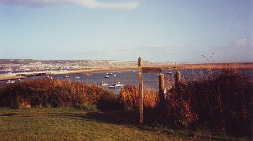 Sign for the Dorset Coastal Path at Chesil Beach Holiday Village In the background is Portland Isle.
