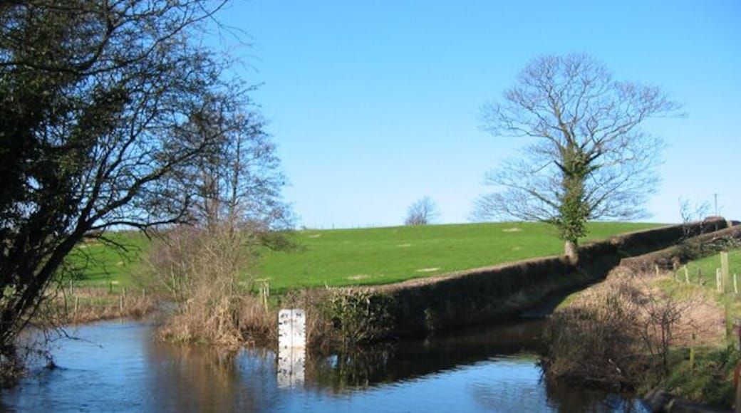 Impassable ford of the River Weaver. Woodcotthill Road apparently once forded the River Weaver (left to right foreground) at this point; however, as the depth gauge (4 ft) reveals, the ford is impassable to vehicles. The road is still marked as a ford to the north but as a no-through road to the south. A footbridge (out of view on right; see this image) allows people and bicycles to pass with dry feet. The River Weaver is here the boundary between the Cheshire civil parishes of Newhall and Wrenbury cum Frith.