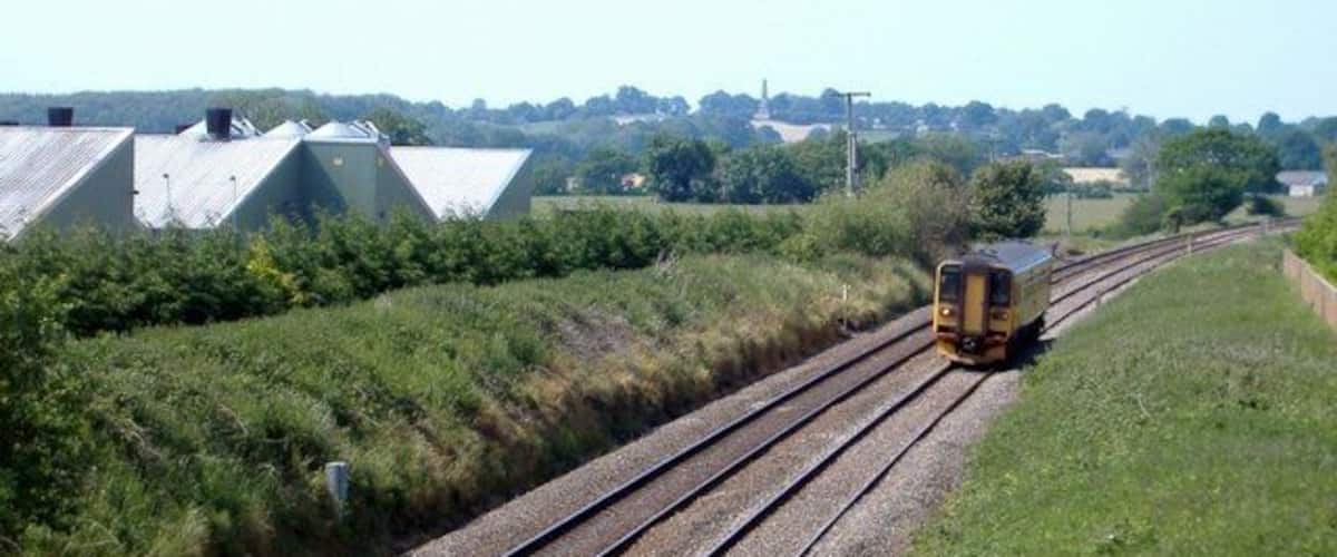 A train on railway tracks with industrial buildings in the background.