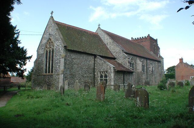 A stone church with a steep roof and a large arched window, surrounded by a cemetery with headstones.