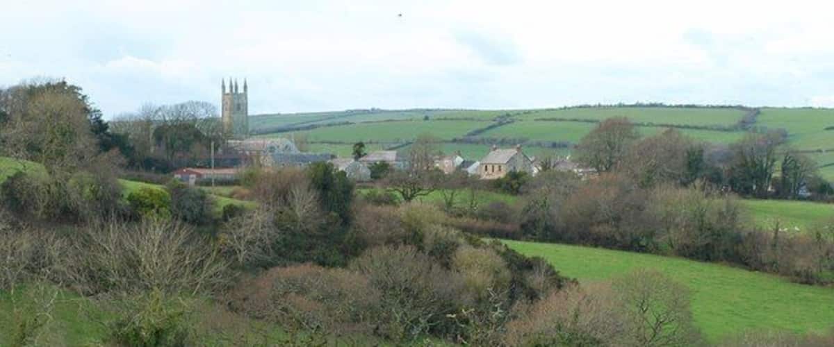 A rural landscape with rolling hills, a church tower, and scattered houses.