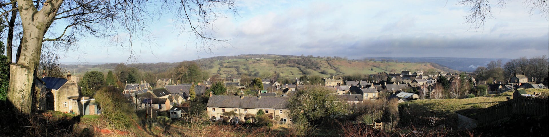 Winster is a well-preserved Derbyshire village west of Matlock. The vantage point of this composite photo is The Flat at the top of the lower branch of East Bank. It's just southwest of the Old Lead Mines near the centre of this 1899 map. Until the Leacroft Road estate was built in the mid 20th century, Winster comprised the three roads shown in the 1899 map. The most important, Main Street, is in the north of the village and runs east/west. South of Main Street the land rises towards the high ground known as Winster Bank. Two roads that lead south from Main Street and towards the Bank are known as West Bank and East Bank. This shot looks north so West Bank is to the left and East Bank is to the right. About half way up the hill, East Bank divides into two with one branch leading southwest and ending up as The Flat – the point from which this photo was taken. The other branch initially leads southeast but soon swings right and continues in a westerly direction until it joins West Bank at the point marked as Winster Bank on the map. The places that I've identified in notes include the tower of St John the Baptist's Church, Birchover Wood, the Dower House, West Bank House, Winster Hall, the Burton Institute and the former Tallow Factory.