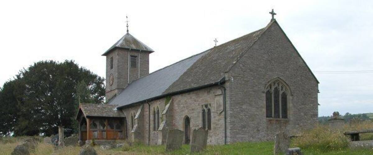 A stone church with a bell tower and a graveyard.