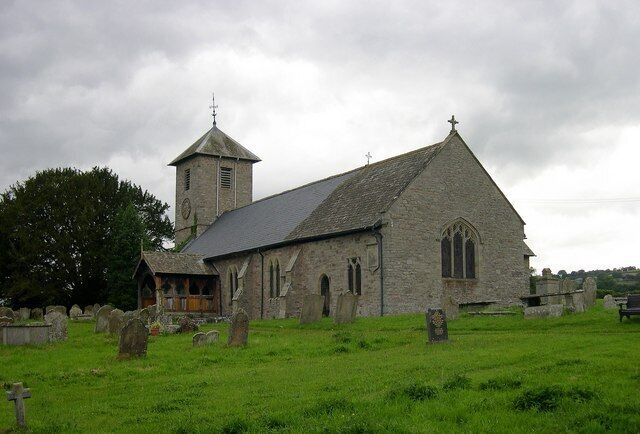 A stone church with a bell tower and a graveyard.