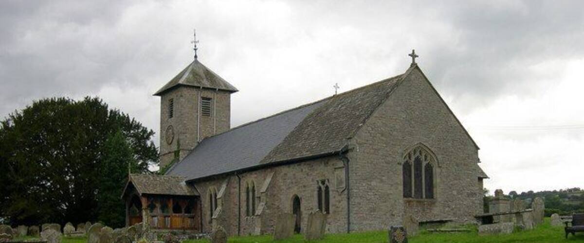 A stone church with a bell tower and a graveyard.
