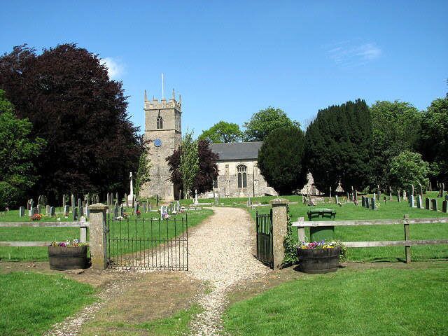 A church with a tower, surrounded by a cemetery with headstones and a pathway leading to the entrance.