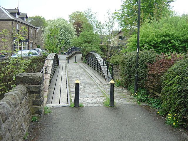 A stone bridge over a narrow path with greenery on both sides.