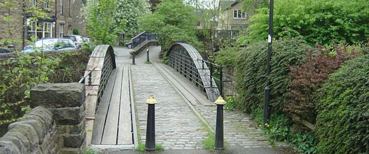 A stone bridge over a narrow path with greenery on both sides.