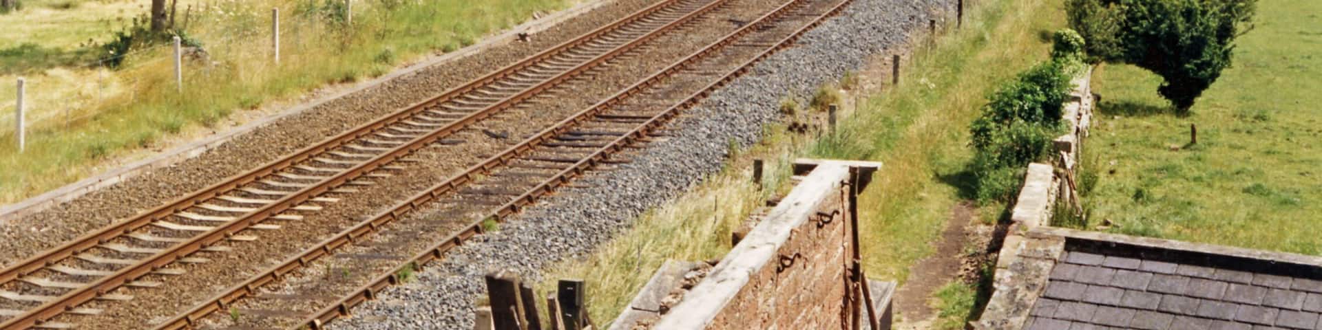 Site of Curthwaite station, 1986. View eastward, towards Carlisle: ex-Maryport & Carlisle Workington - Maryport - Carlisle secondary main line. The station had been closed from 12/6/50 (goods, 6/1/58), but the line remains active.