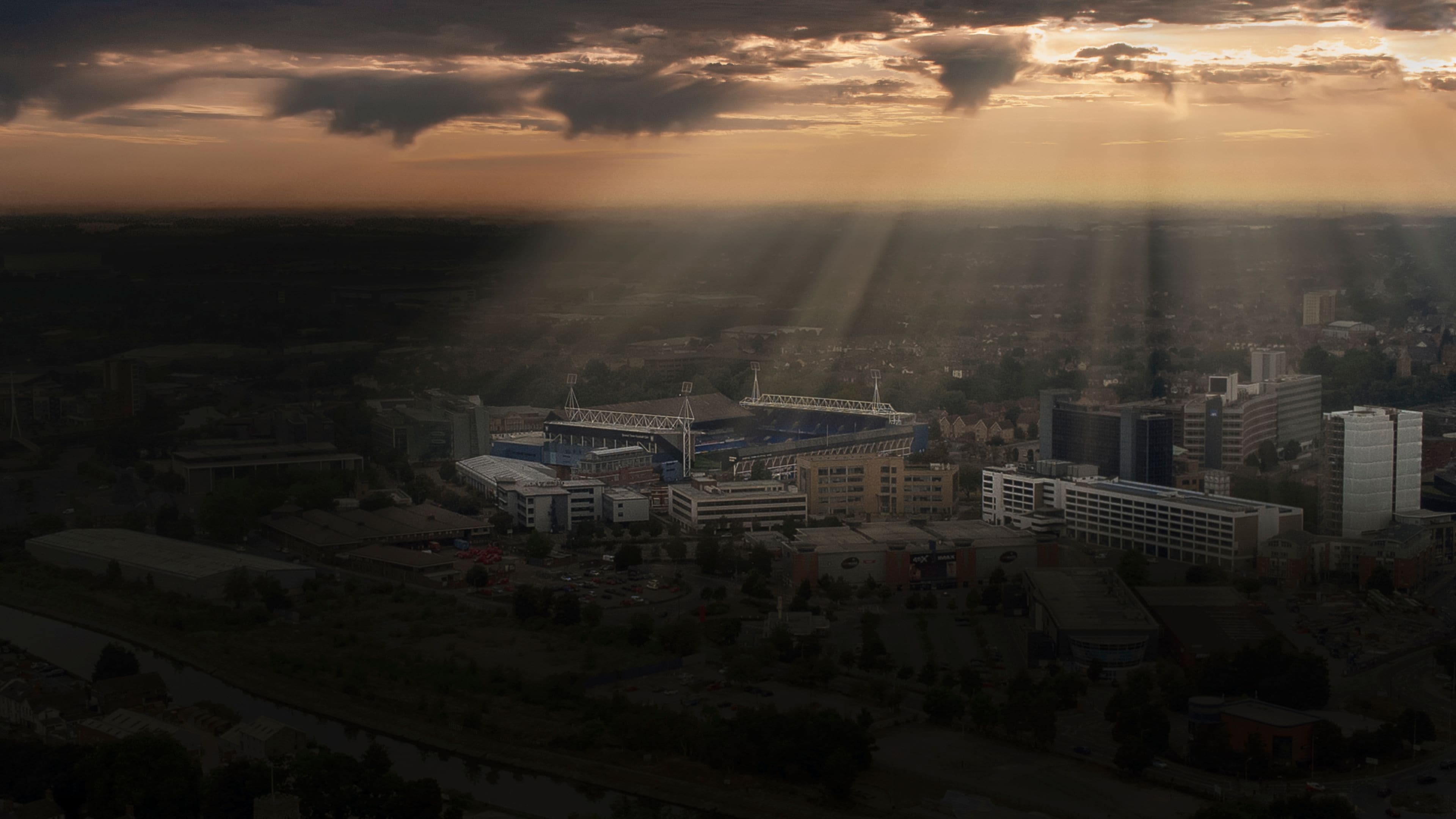 Un paisaje urbano que incluye un estadio, edificios y un río.
