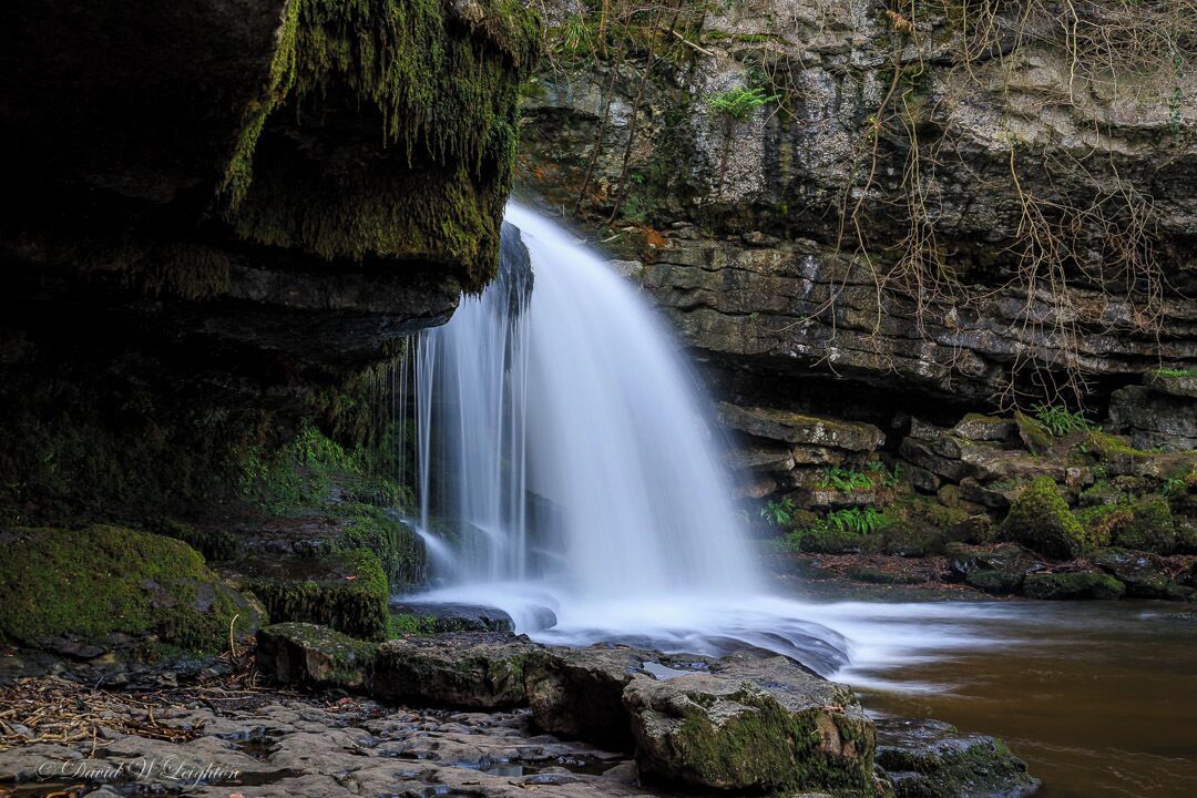 A waterfall cascading down a rocky cliff into a river.