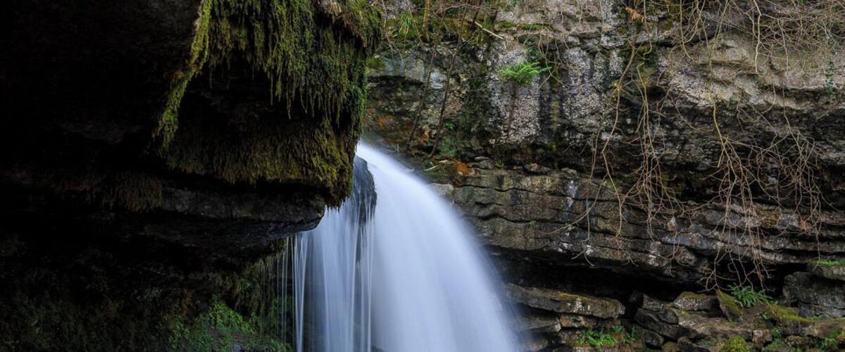 A waterfall cascading down a rocky cliff into a river.