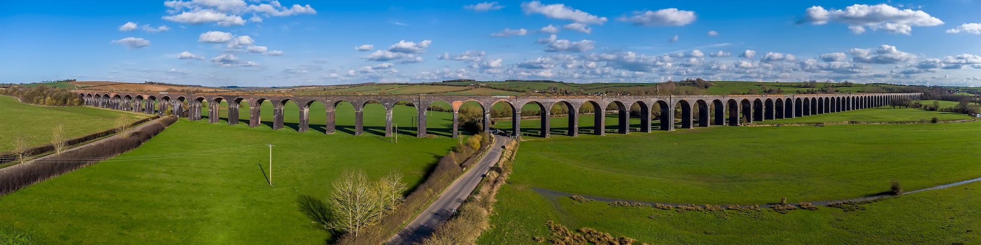 Un largo viaducto cruza un valle verde bajo un cielo despejado.