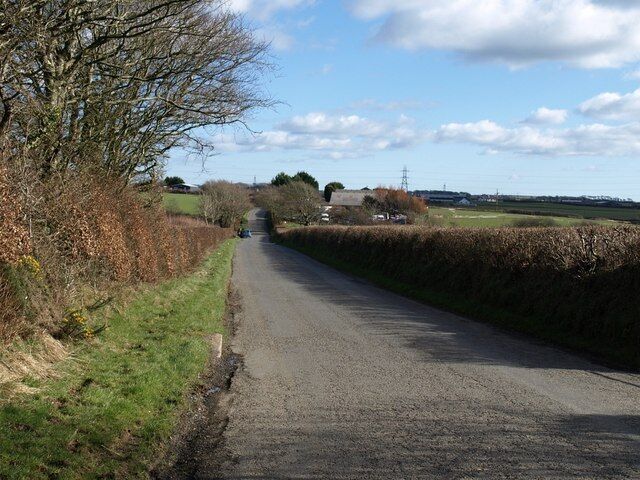 Greena Moor A fairly unwavering road crosses this part of Cornwall between straight field boundaries southeast of Week St Mary. Here it descends beside trees to pass a small commercial site.
