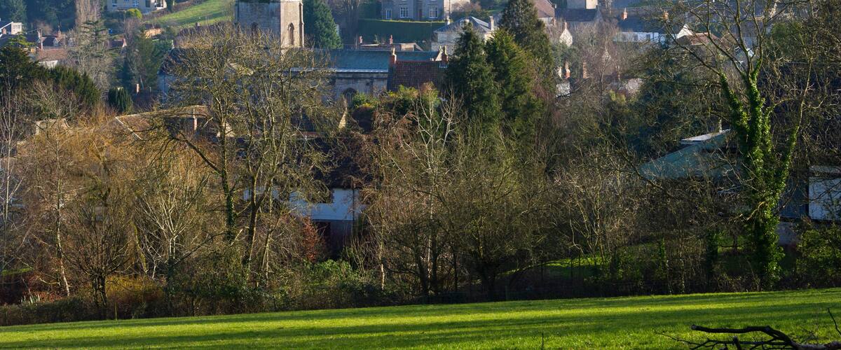 A village with a prominent church tower, houses, and a green field.