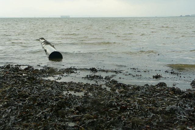 Waiting for the tide to go out. I am waiting to see if I can get into SU4903 about 100 metres in this direction. I am using this abandoned pipe as a guide to the height of the water. At 14:23 it does not look too promising. But the tide runs out quickly here, see 1147216