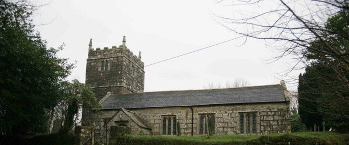 A stone church with a tower and a well-maintained lawn.