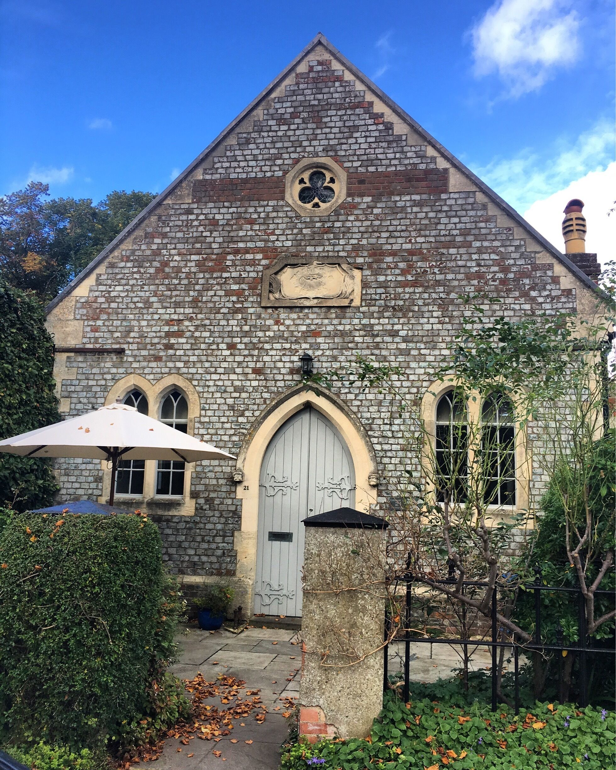 A stone building with a triangular roof, arched windows, and a large door.