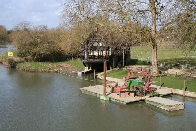Boathouse by the Bridge The boathouse is probably Victorian and for many years was used as a boathouse. It was bought by someone and made into a dwelling and the boat mooring filled in. I see now that has been dug out again so boats can be moored. The big problem with living here is that it floods and the only way to get to it is by rowing a boat. I could not tell you what the barges are for in the foreground.