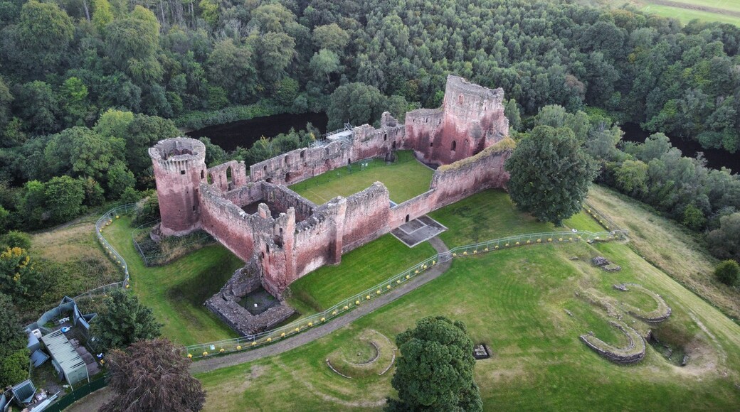 Une vue aérienne d’un château historique, entouré d’une végétation luxuriante et d’un fossé.